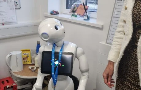 A Robot With An Ipad On Its Chest Looks At A Person.
