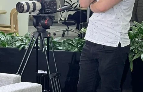 A Man Checks The Shot On A Camera In Front Of A Light.
