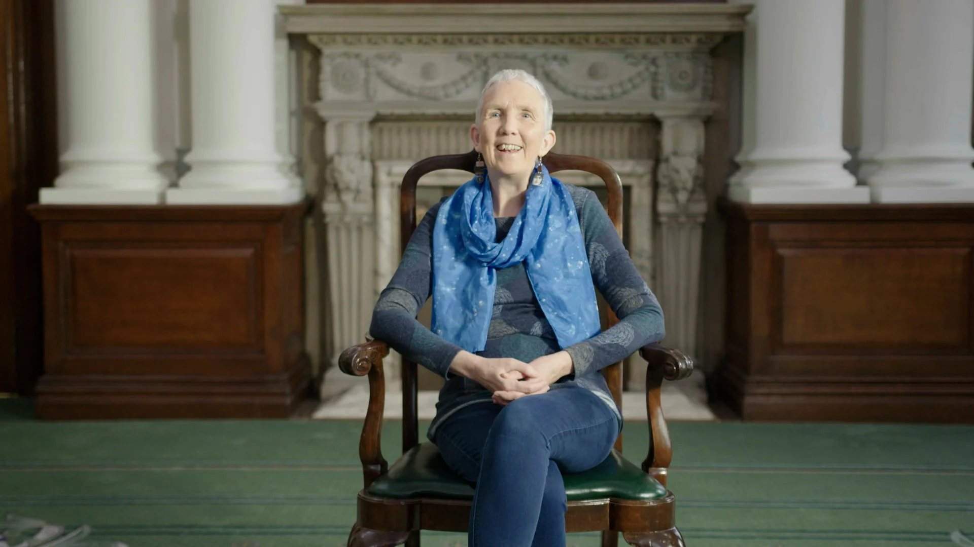 Anne Cleeves Smiling Whilst Sat In A Chair In A Large Room.