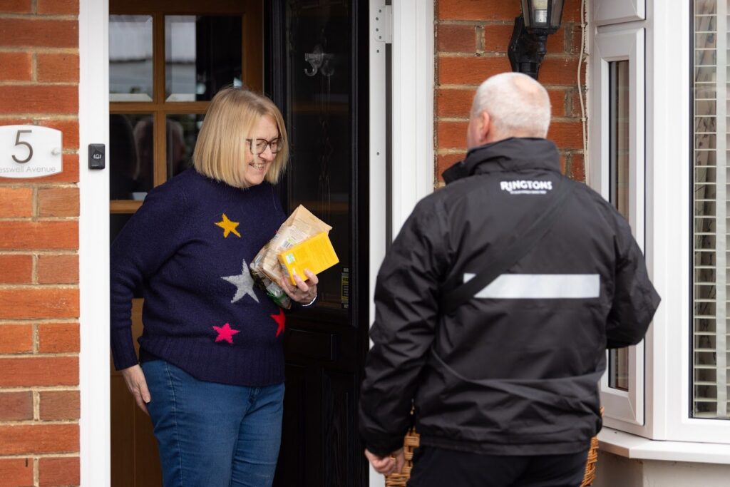 A Ringtons salesperson handing over a delivery at a customer's door